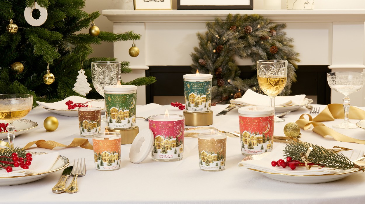 Photo d'une tablée de Noël avec des bougies de différentes couleurs disposées sur une table festive. Sapin de noël  en arrière plan.