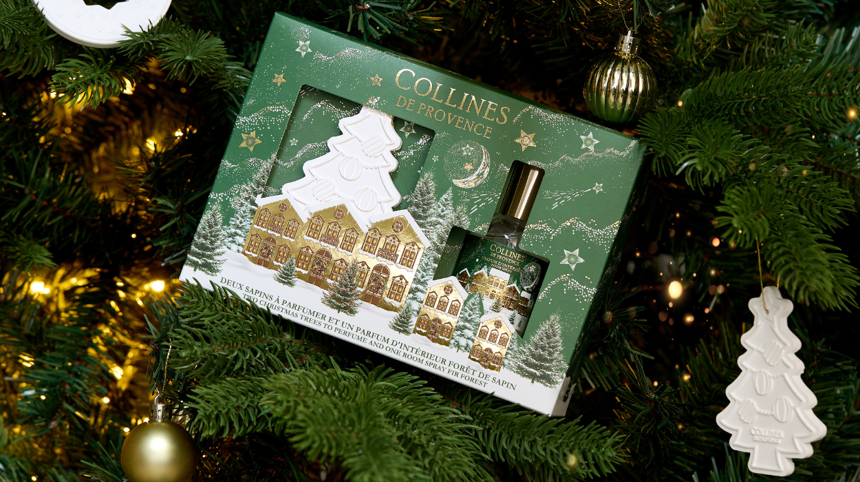 coffret cadeau rose comprenant un parfum d'ambiance et une céramique en forme de sapin disposé sur des cadeaux 